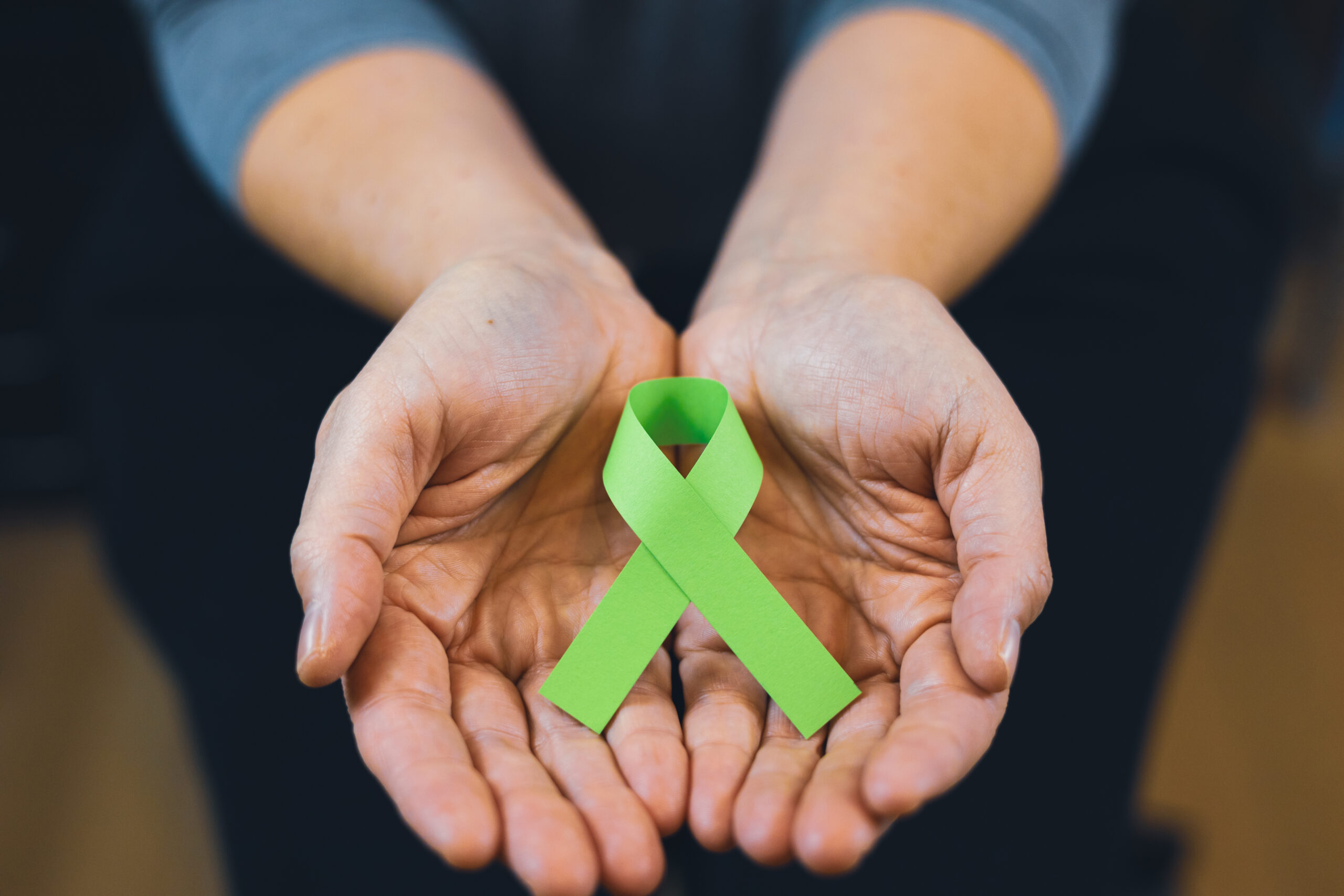 Woman holding a green mental health ribbon.