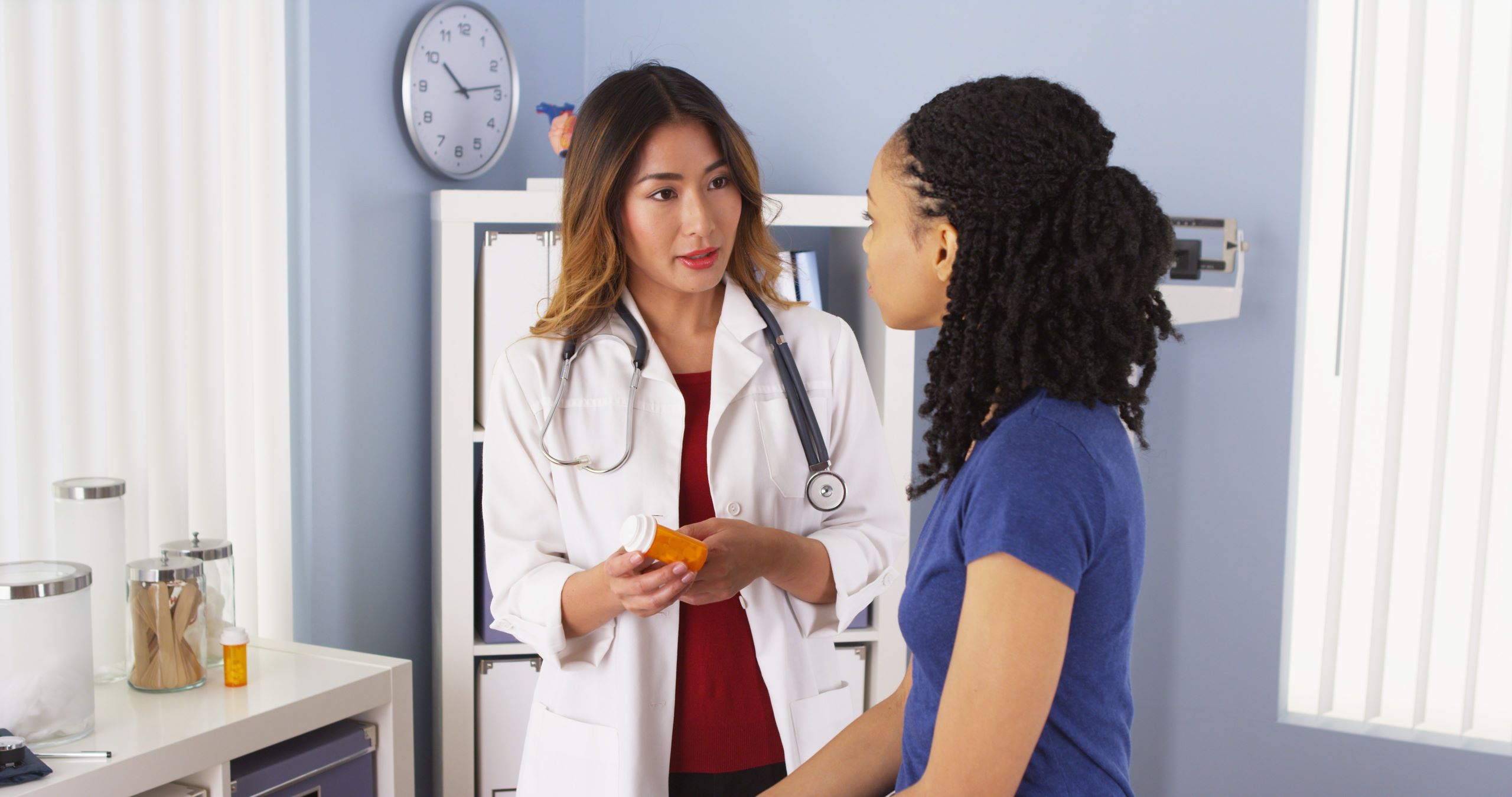 asian female doctor explaining medication to a young black female patient