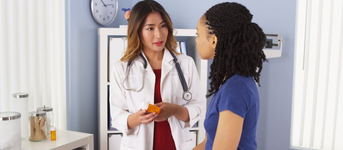 asian female doctor explaining medication to a young black female patient