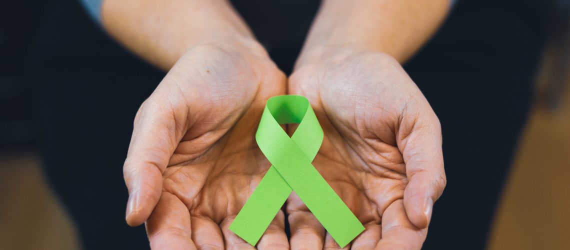 Woman holding a green mental health ribbon.